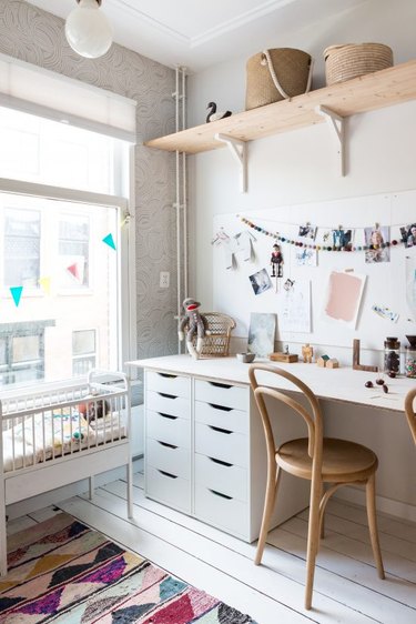 Kids' bedroom desk in all-white palette with pink accents and Scandinavian furniture