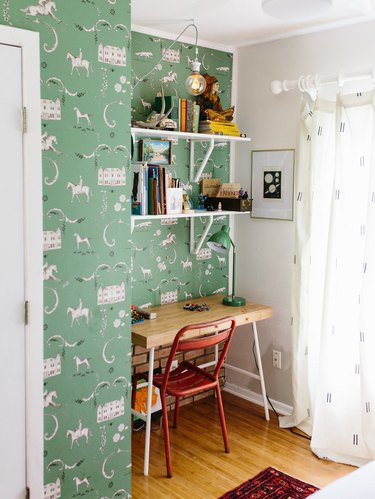 Kids' bedroom desk with green patterned wallpaper and vintage decor