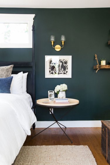 dark green bedroom with woven rug and brass light