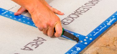 Cementboard being scored with knife.