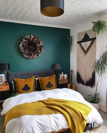 Bedroom with teal accent wall, gray headboard and yellow pillow and throws