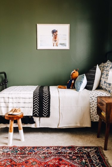 green kids bedroom idea with sage green walls and patterned bedding with area rug on floor