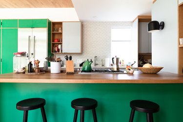 Kitchen counter, green paint, black counter stools, wood countertop