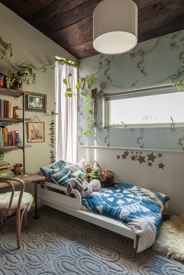 bohemian kids bedroom idea with botanical wallpaper and plants draped around windows