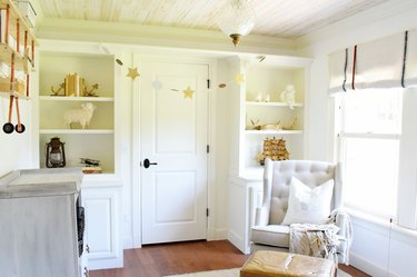French farmhouse nursery idea with built-in shelving and tufted wingback rocking chair
