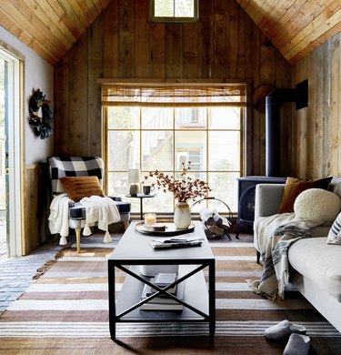 cozy living rooom with wood paneled walls and a buffalo check wingback chair