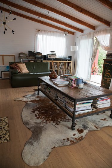 Sloped ceiling with beams, animal skin rug, and coffee table