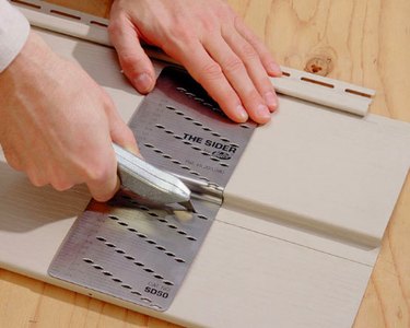 Cutting vinyl siding with a knife.