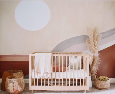 nursery idea for 2020 with warm earth tones and artistic mural on wall