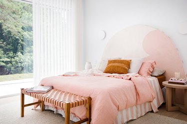 bedroom furniture idea with upholstered headboard and matching bedding near large open window