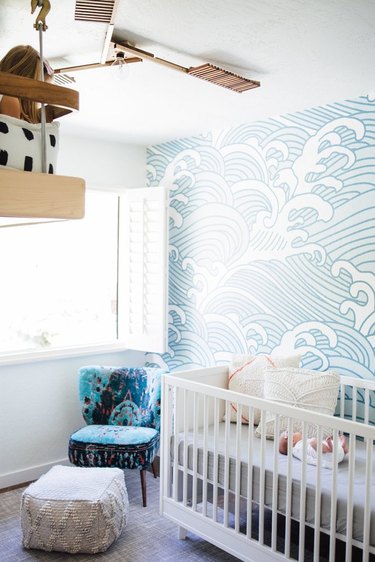 blue nursery idea with mural wallpaper and white crib near window with shutters