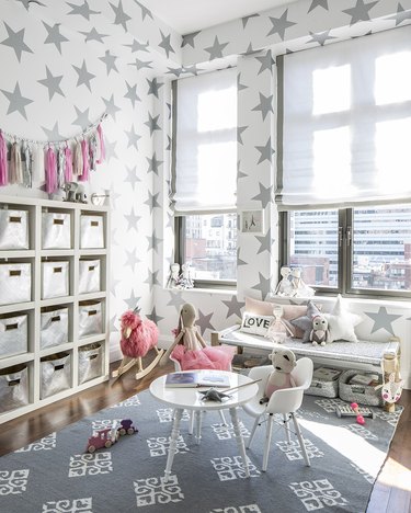kids playroom idea with star wallpaper and white furniture with hot pink toys