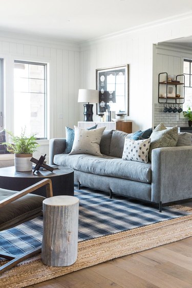 traditinal living room with plaid rug layered over a jute rug