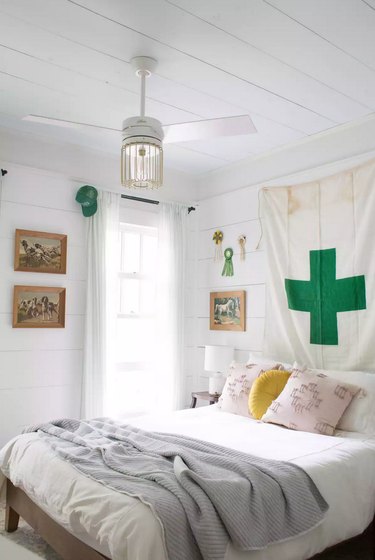 kids' bedroom idea with all-white palette and pops of green with tapestry on shiplap walls