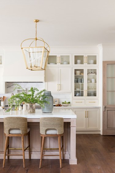 white kitchen space with two stools and hanging light fixture