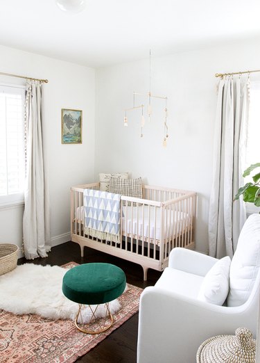modern nursery idea with white walls and layered rugs with wooden crib