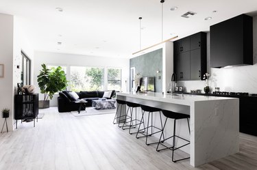 alley-style kitchen and living room with grey hardwood