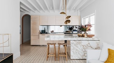 large open kitchen with modern brass chandelier above marble island