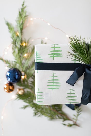 Beautifully wrapped present in white kraft paper with watercolor Christmas trees