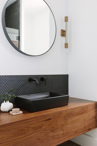 small bathroom backsplash ideas with small black subway tile with black circle mirror and gold light