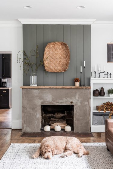 Concrete fireplace with shiplap wall, basket.