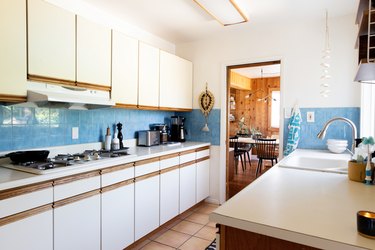 white kitchen with blue backsplash and tiled floor