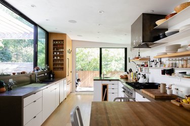 galley kitchen with large windows, butcher block countertops, dog looking outside
