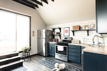 kitchen with L-shaped cabinets painted blue with a white backsplash