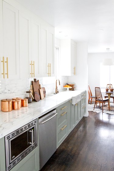 white kitchen with green lower cabinets and brass pulls