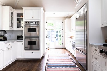 sunny kitchen with striped rug, dual stoves, stainless steel appliances, hardwood floors