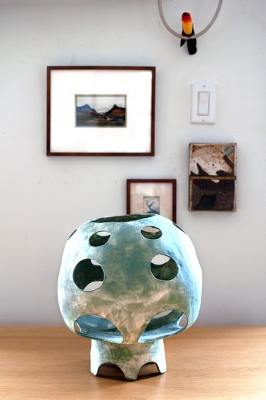 sculpture on a table with framed artwork in the background