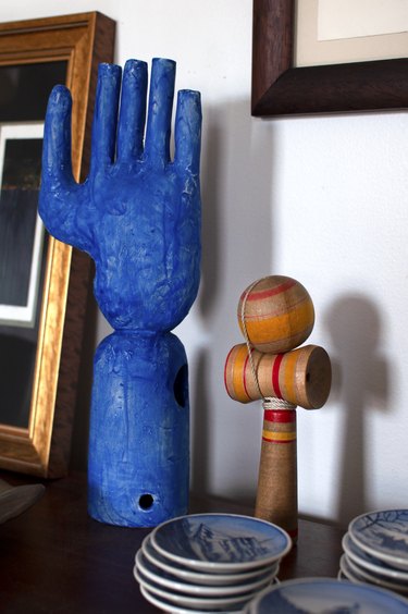 sculptural objects on a table, including a bright blue hand sculpture