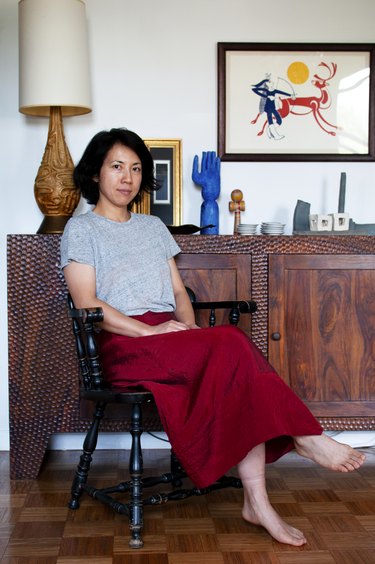 figure sitting on black chair near wooden cabinet