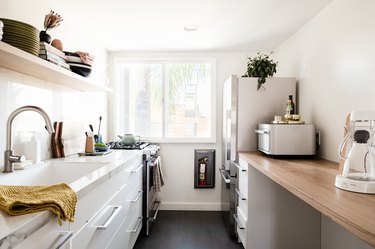 galley kitchen with white cabinets, white walls, wood countertop