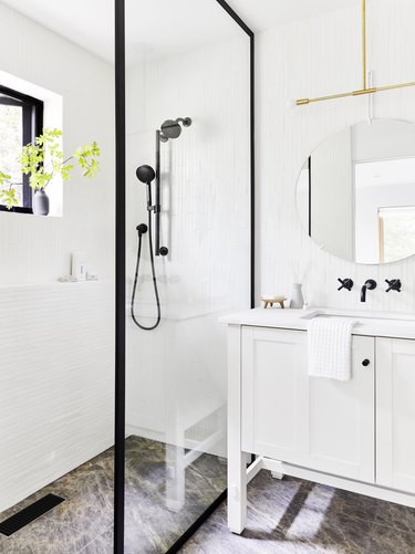 white modern bathroom with black shower fixtures and black trim around glass partition and black fixtures