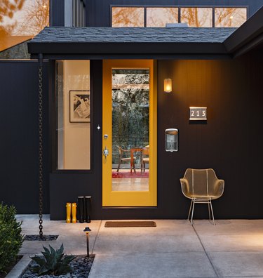 Yellow midcentury modern front door with midcentury hardware and black exterior