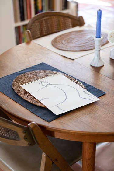 dining table with artwork and blue candlestick nearby