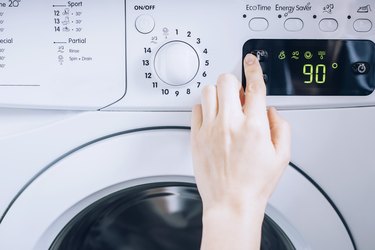 person touching the screen of a white washing machine