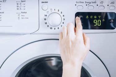 person using white washing machine with temperature controls