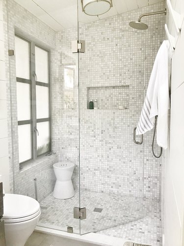 Enclosed shower with gray mosaic tile on floor and walls