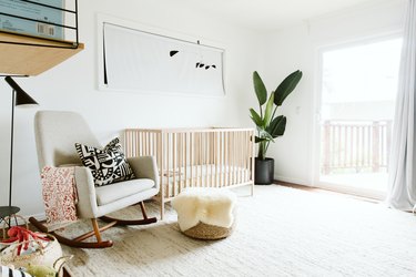 White baby nursery idea with light wood crib and rocking chair