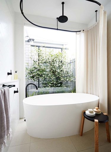 modern bathtub shower combination with oval tub and large window
