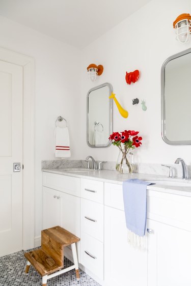 bathroom space with white cabinets and two mirrors