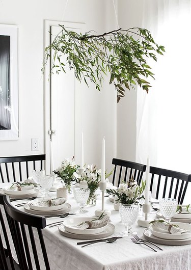 modern white dining room with black chairs and greenery