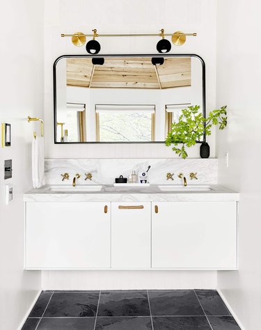 bathroom space with black floor, white cabinets, and one large mirror