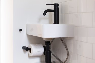 focus on sink with black hardware and tiled wall behind it