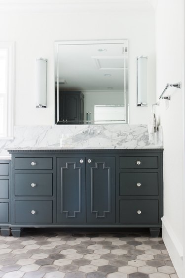 bathroom space with gray and white tiles and dark cabinets