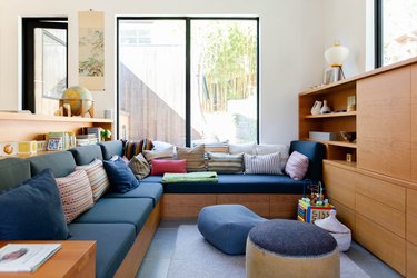 Modern blue kids' playroom idea with wood furniture and throw pillows
