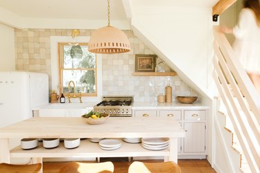 neutral kitchen with a pendant lamp and wooden island and backsplash