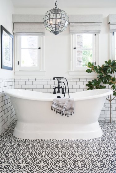 bathroom tub backsplash idea with white subway tile and black grout behind freestanding tub